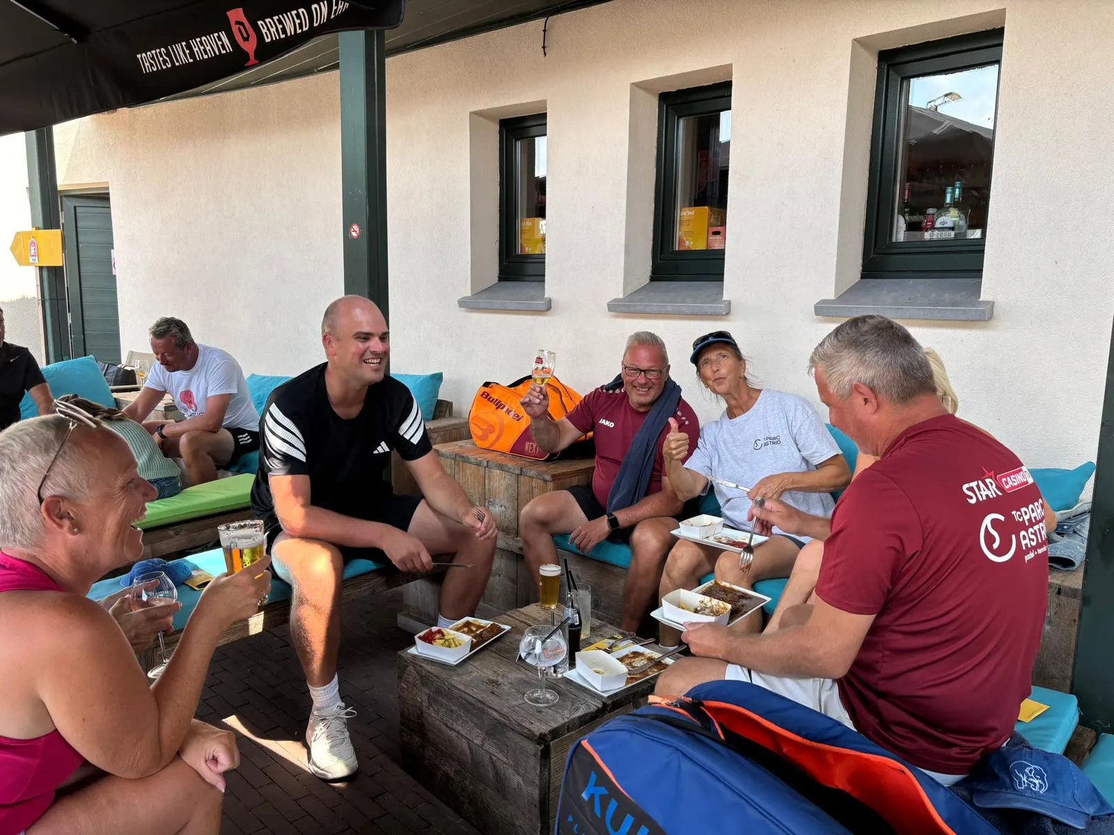 Leden eten en drinken samen op het terras van de clubbar